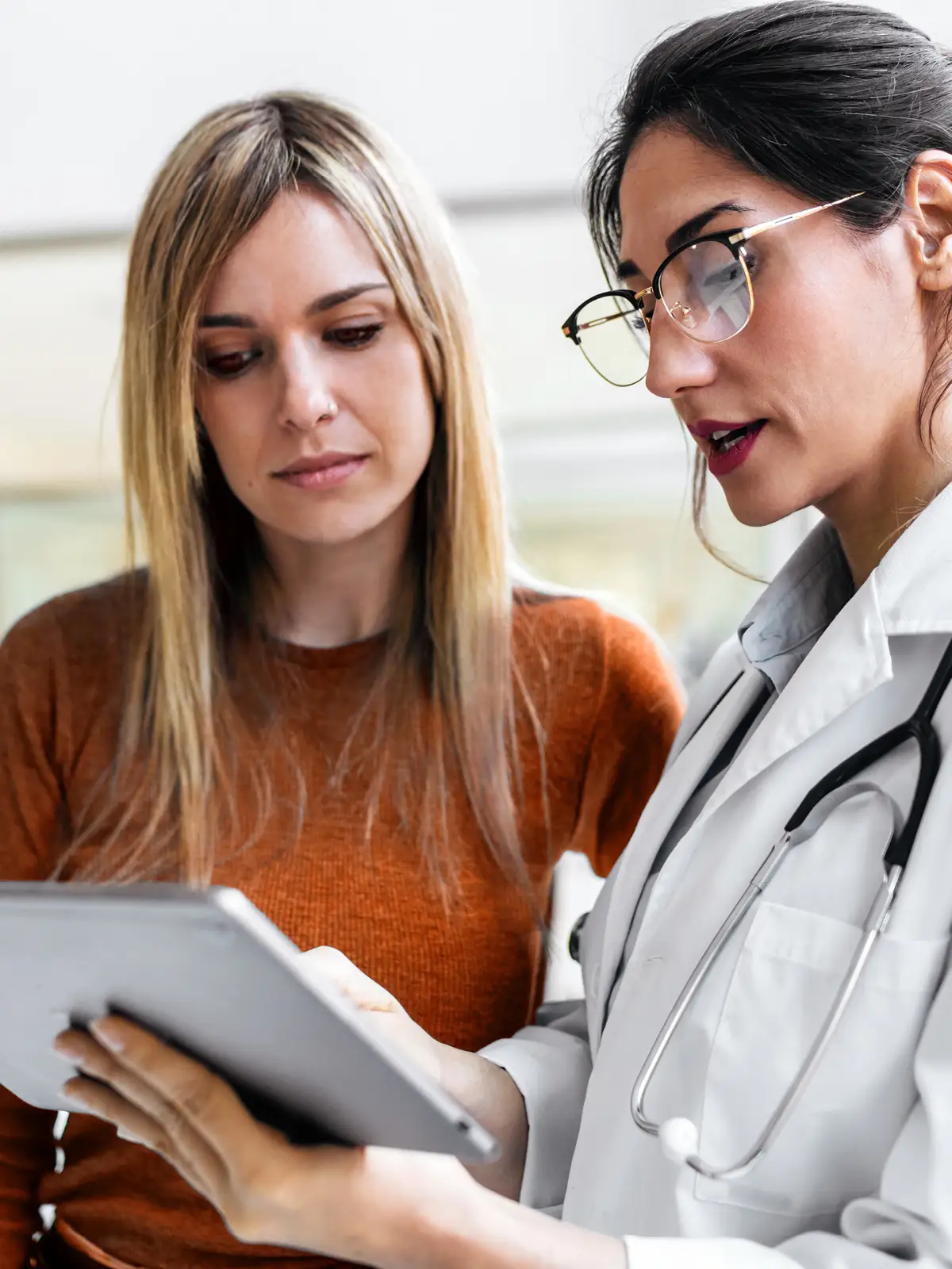 Eine Ärztin berät ihre Patienten. Beide schauen sich etwas auf dem Tablet an. | VIACTIV Krankenkasse
