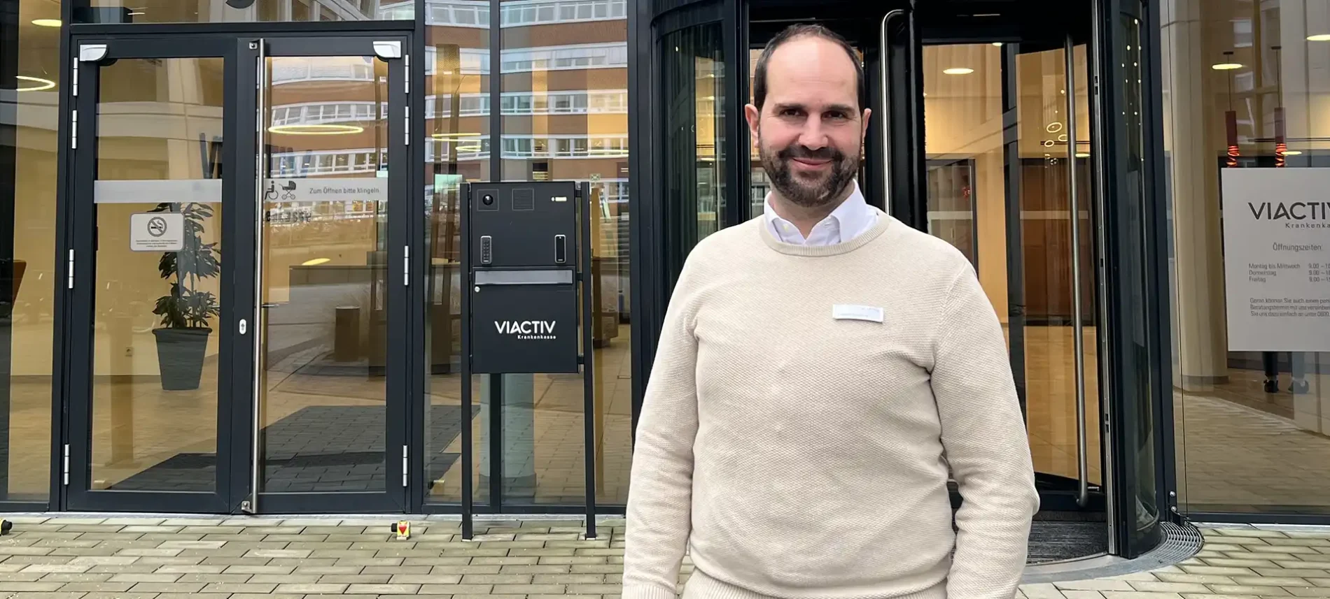 Ein Mitarbeiter der VIACTIV steht draußen vor dem Eingang des VIACTIV Gebäudes. | VIACTIV Krankenkasse