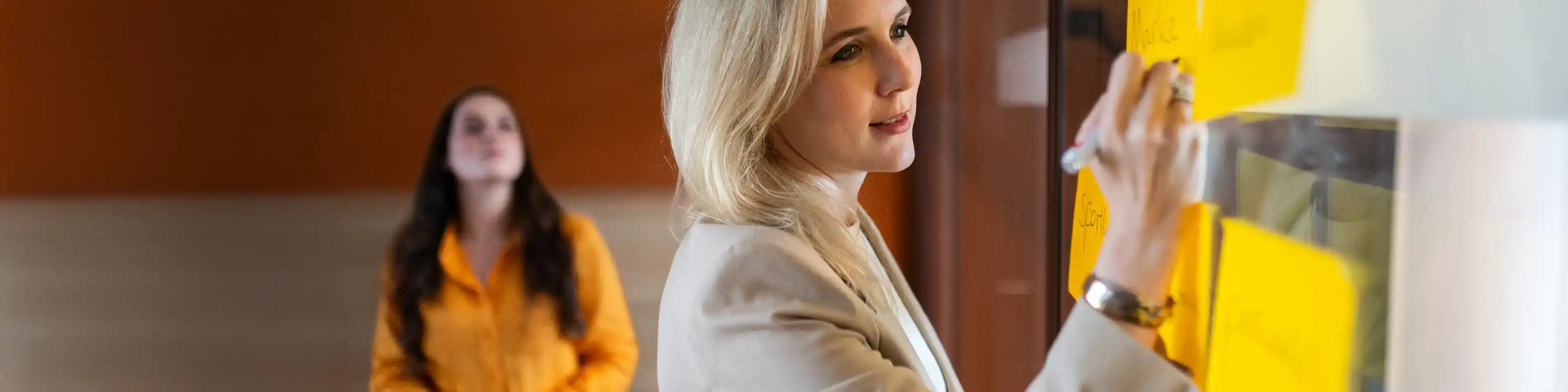 Eine VIACTIV Mitarbeitende notiert etwas auf einem Zettel. Die Zettel kleben an einer Wand. | VIACTIV Krankenkasse