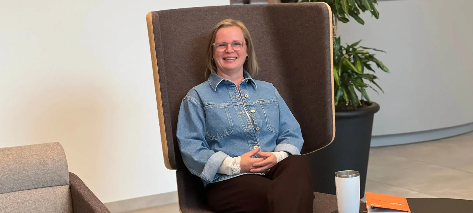 Mitarbeiterin Andrea Bromm sitzt auf einem Stuhl in der VIACTIV Krankenkasse. | VIACTIV Krankenkasse