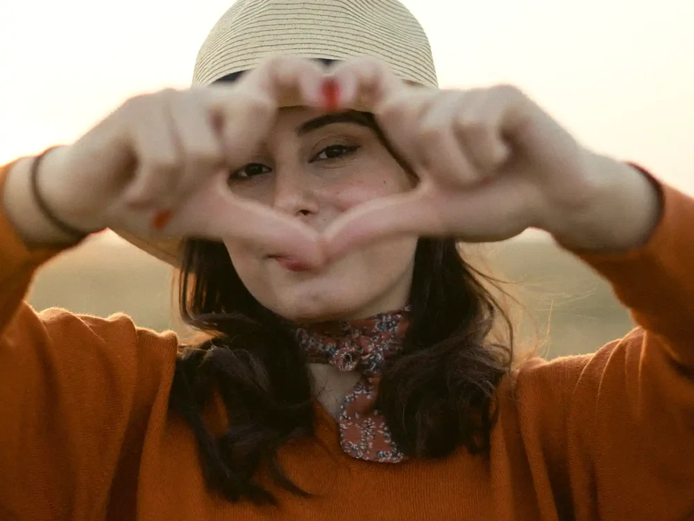 Eine junge Frau formt mit ihren Fingern ein Herz in die Kamera. | VIACTIV Krankenkasse