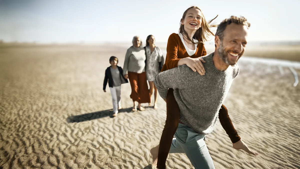 Eine Familie macht einen Ausflug am Strand. Sie sehen glücklich aus. | VIACTIV Krankenkasse