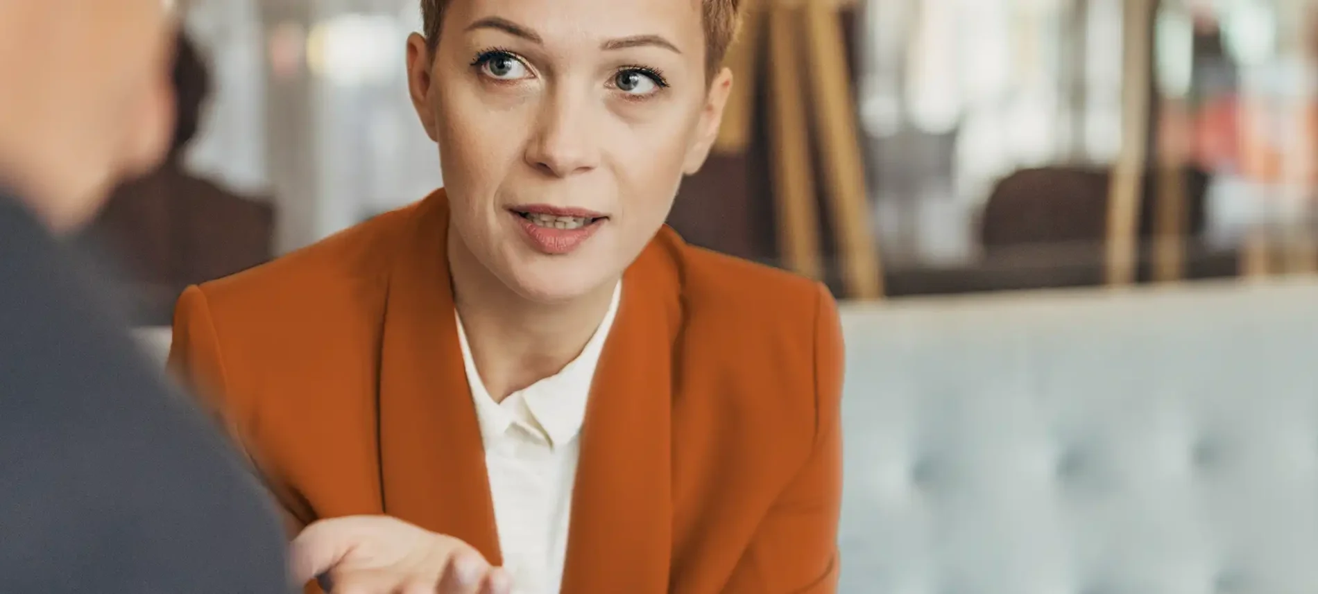 Eine Frau sitzt auf dem Sofa. Ihr gegenüber sitzt ein älterer Mann, mit dem sie sich unterhält. | VIACTIV Krankenkasse
