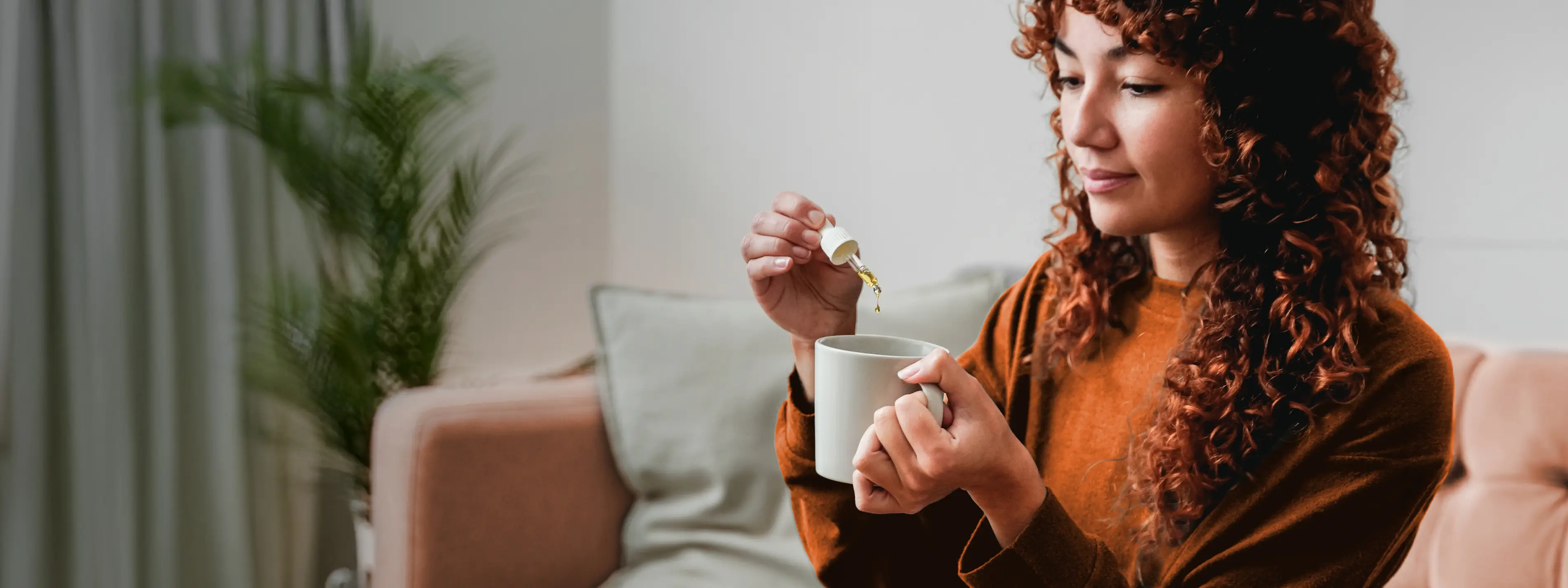 Eine junge Frau tropft sich pflanzliche Arzneimittel in ihr Getränk. | VIACTIV Krankenkasse