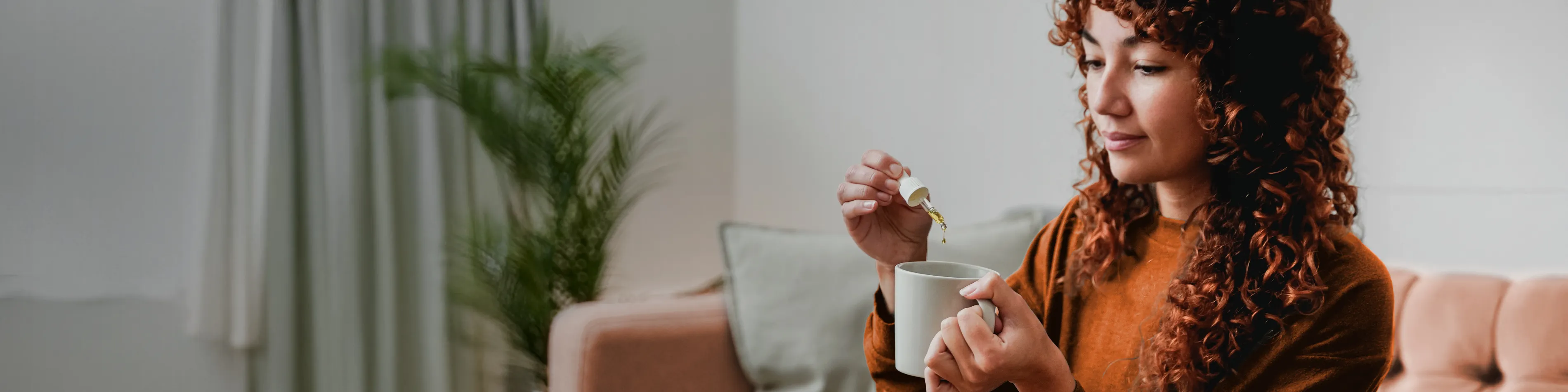 Eine junge Frau tropft sich pflanzliche Arzneimittel in ihr Getränk. | VIACTIV Krankenkasse