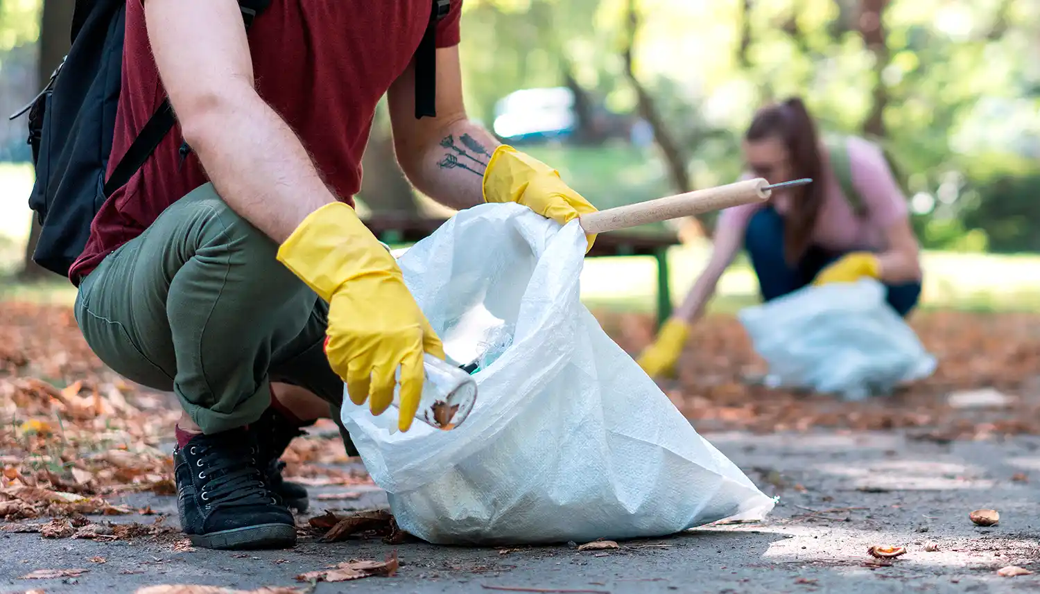 Mehrere Personen sammeln mit Handschuhen in einem Park Müll ein und beteiligen sich an der Plogging Challenge. | VIACTIV Krankenkasse