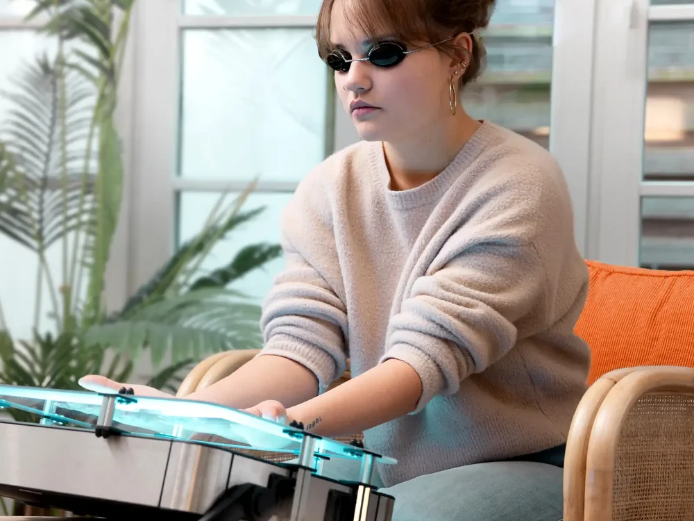 Eine junge Frau sitzt zuhause und macht eine Lichttherapie an ihren Händen. | VIACTIV Krankenkasse