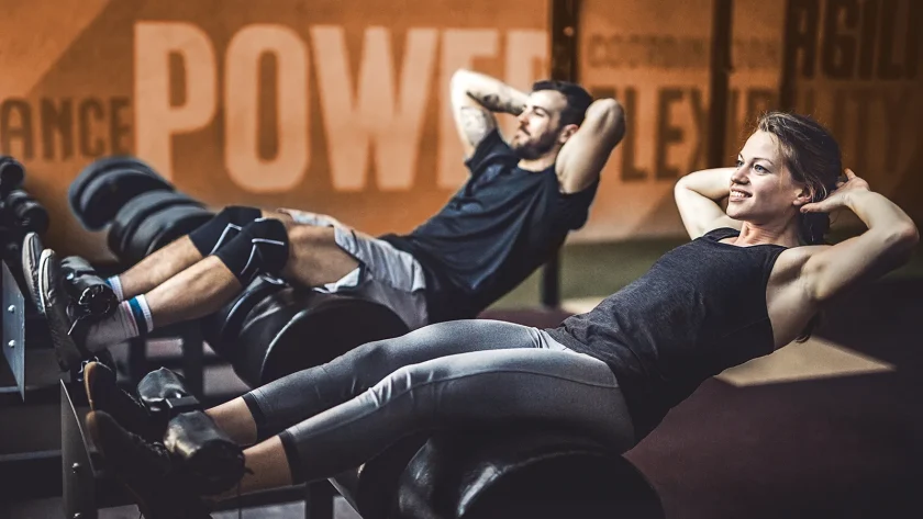 Eine Frau und ein Mann sind im Fitnessstudio und machen dort Sit-ups. | VIACTIV Krankenkasse