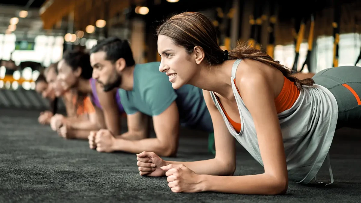 Eine Gruppe von Menschen macht im Fitnesstudio gemeinsam die Übung "Plank". | VIACTIV Krankenkasse