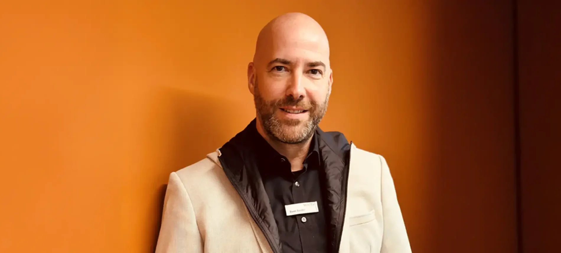 Ein Mitarbeiter der VIACTIV steht vor einer Wand und lächelt. | VIACTIV Krankenkasse