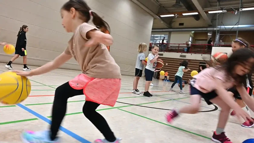 In einer Turnhalle spielen viele kleine Kinder mit Basketbällen. Sie sind voller Freude eifrig mit dabei. | VIACTIV Krankenkasse