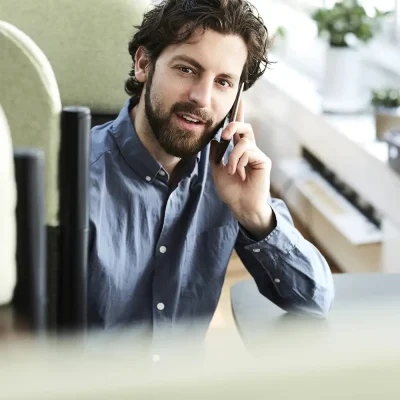 Ein Mann mittleren Alters sitzt im Büro und telefoniert mit seinem Handy. | VIACTIV Krankenkasse