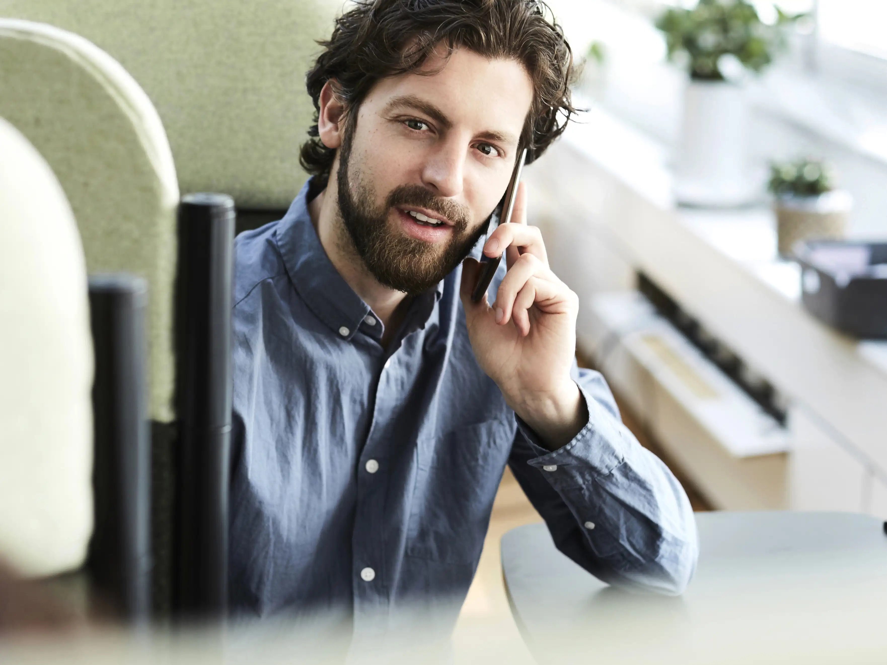 Ein Mann mittleren Alters sitzt im Büro und telefoniert mit seinem Handy. | VIACTIV Krankenkasse