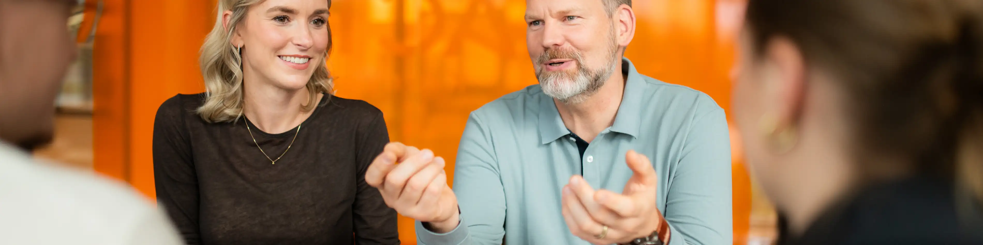 Eine Gruppe von VIACTIV Mitarbeitenden sitzt am Tisch. Sie unterhalten sich. Eine von ihnen hält ein Handy in der Hand. | VIACTIV Krankenkasse