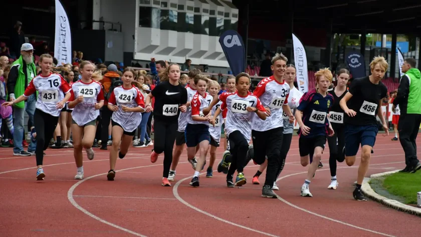 Eine Gruppe mit Jugendlichen läuft auf einem Sportplatz um die Wette. | VIACTIV Krankenkasse
