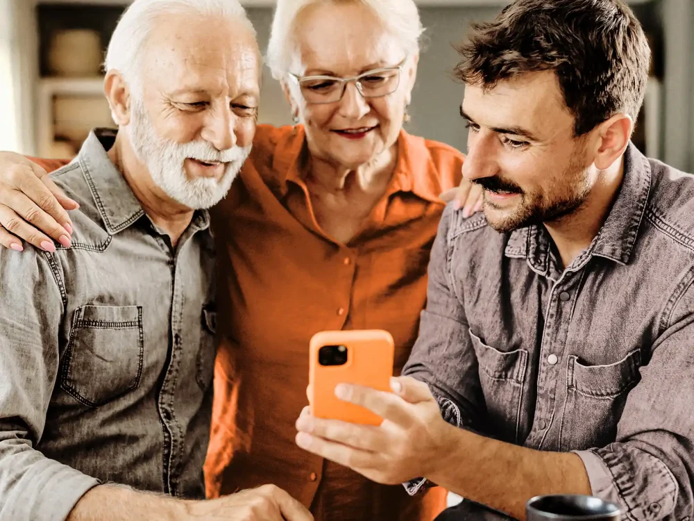 Drei Erwachsende schauen gemeinsam auf ein Handy-Display. Sie informieren sich über Gesundheitsthemen. | VIACTIV Krankenkasse