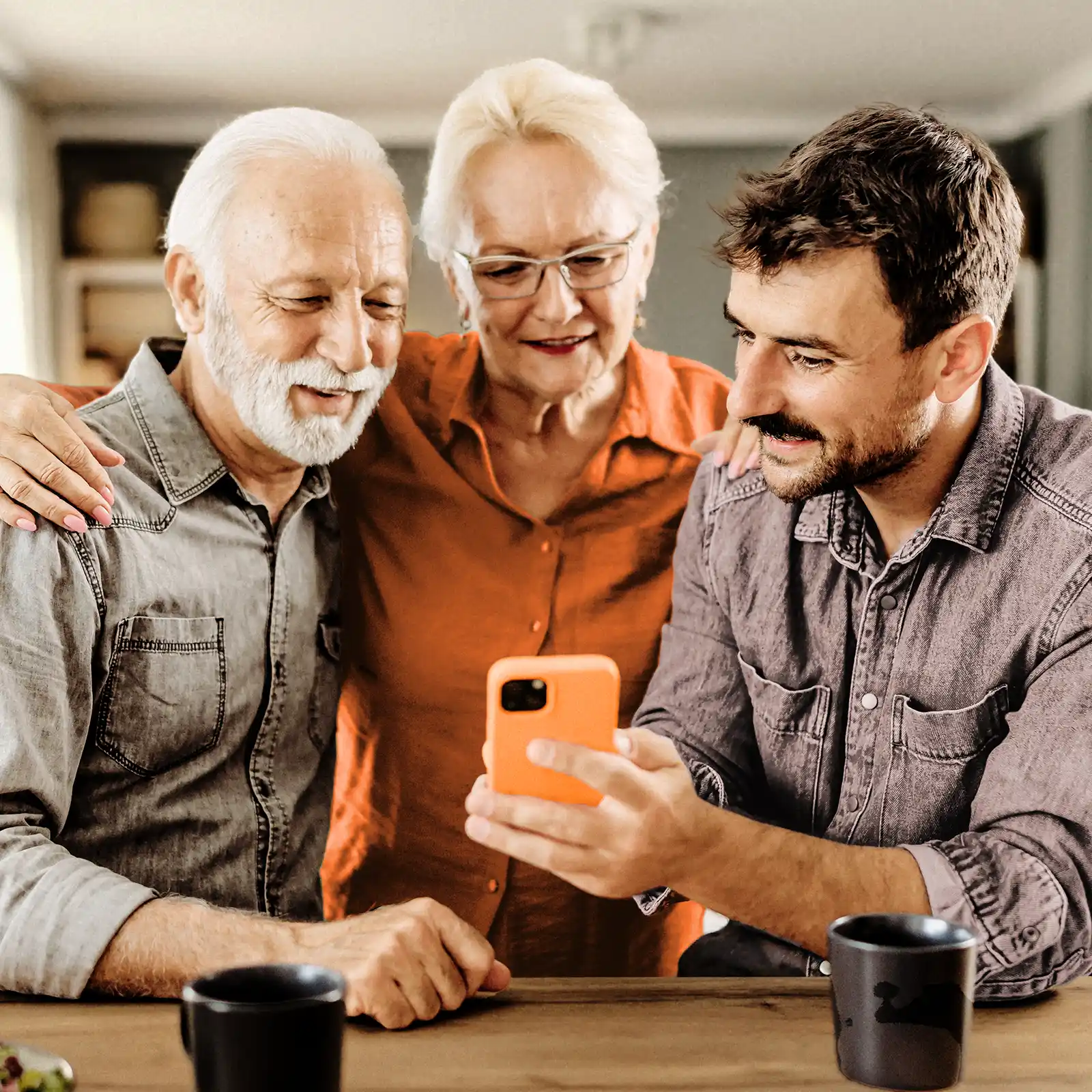 Drei Erwachsende schauen gemeinsam auf ein Handy-Display. Sie informieren sich über Gesundheitsthemen. | VIACTIV Krankenkasse