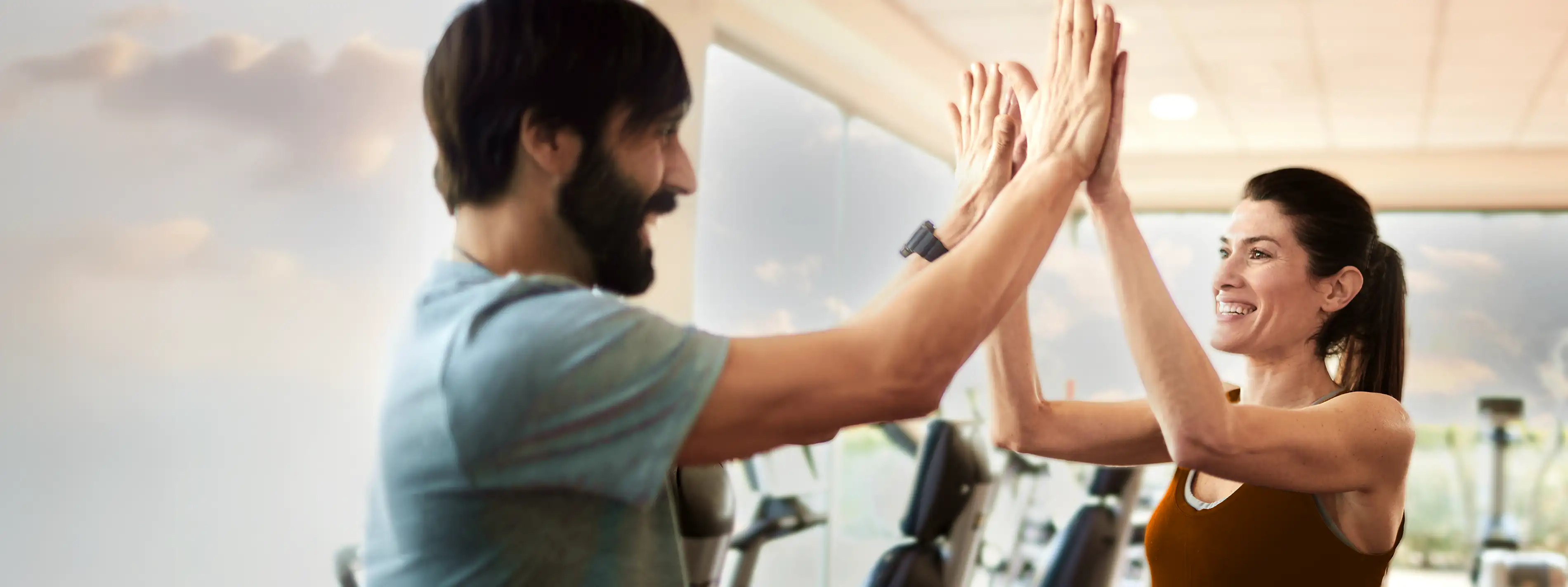 Ein Mann und eine Frau klatschen sich im Fitnessstudio mit den Händen ab. | VIACTIV Krankenkasse