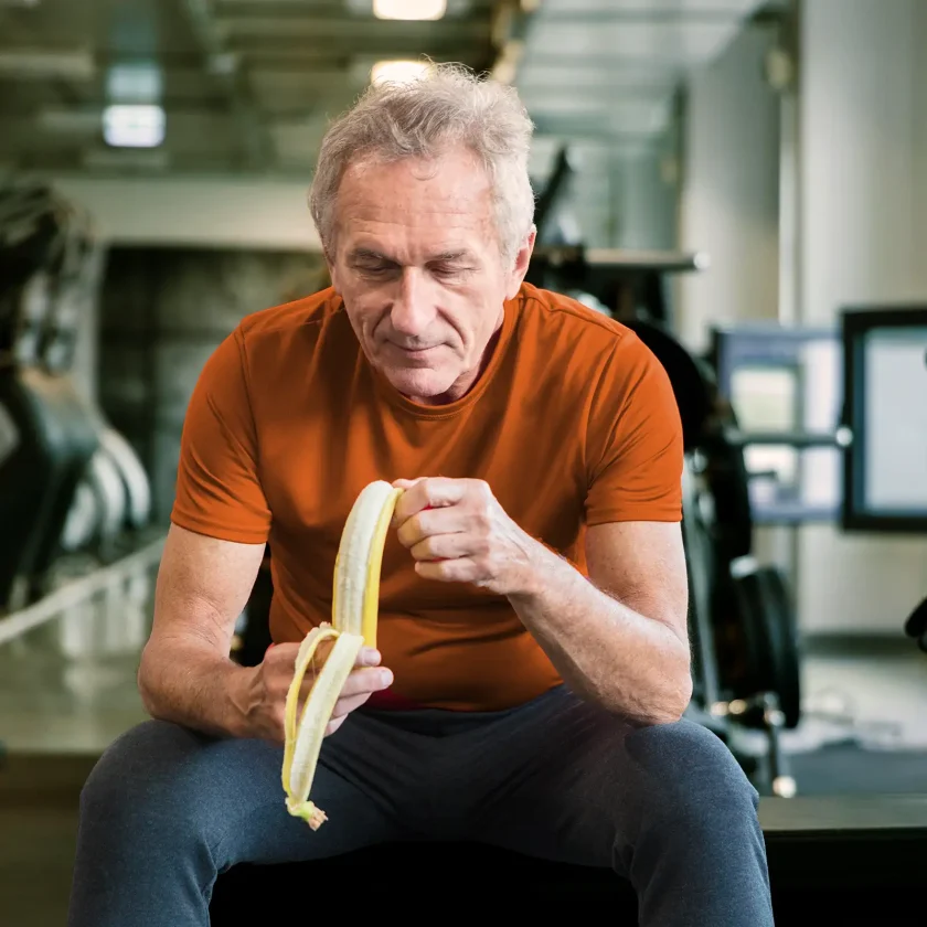 Ein Mann im Fitness-Studio schält eine Banane. | VIACTIV Krankenkasse