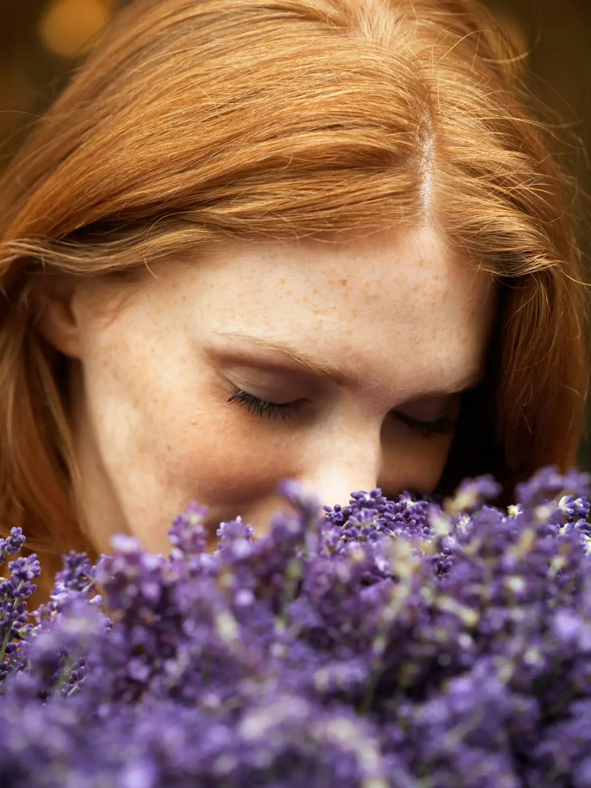 Eine Frau mit rötlichen Haaren riecht an einem Strauß Lavendel und hat die Augen geschlossen. | VIACTIV Krankenkasse