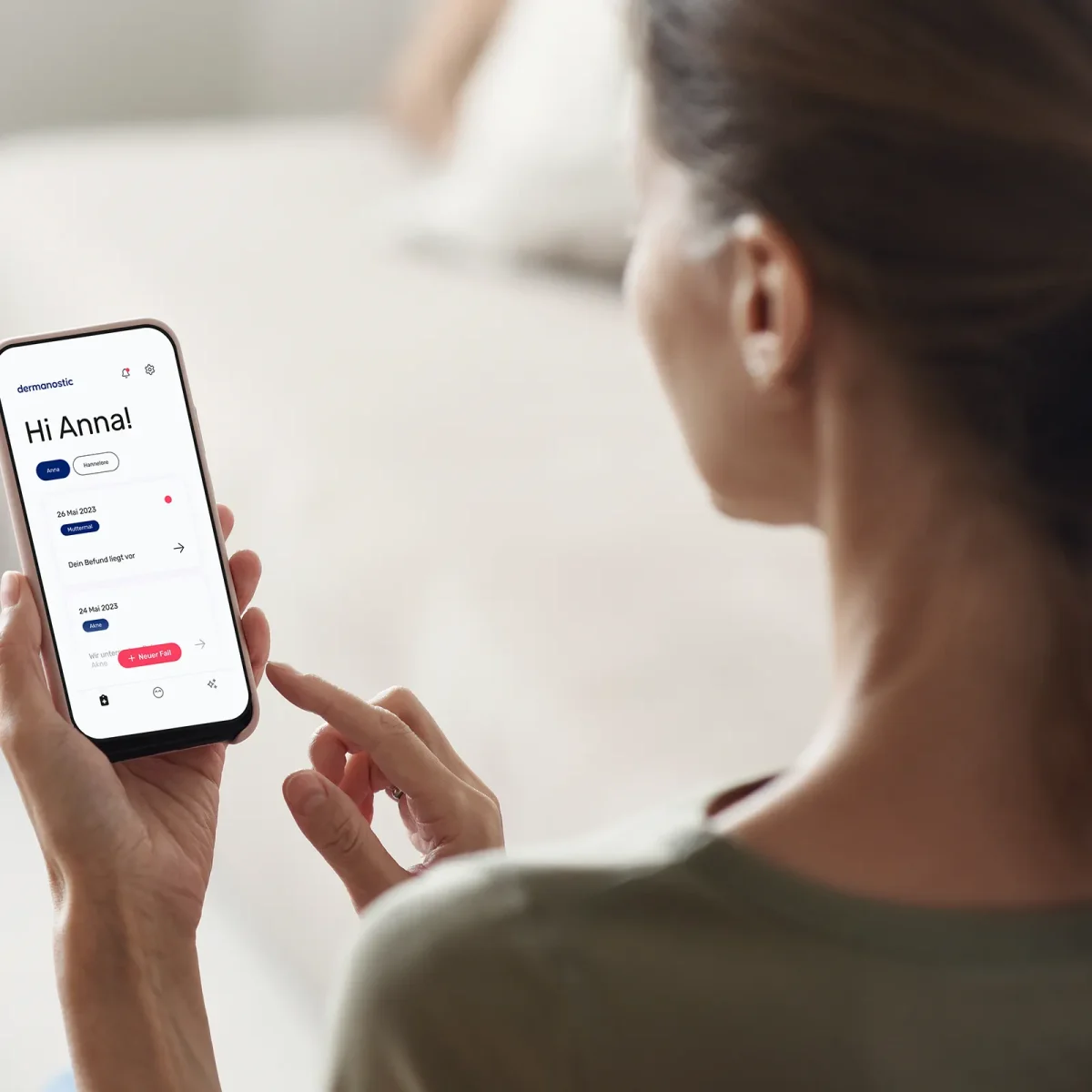 Eine Frau hat die Hautarzt-App von Dermanostic auf ihrem Smartphone geöffnet. Sie schaut auf ihr Handy. | VIACTIV Krankenkasse